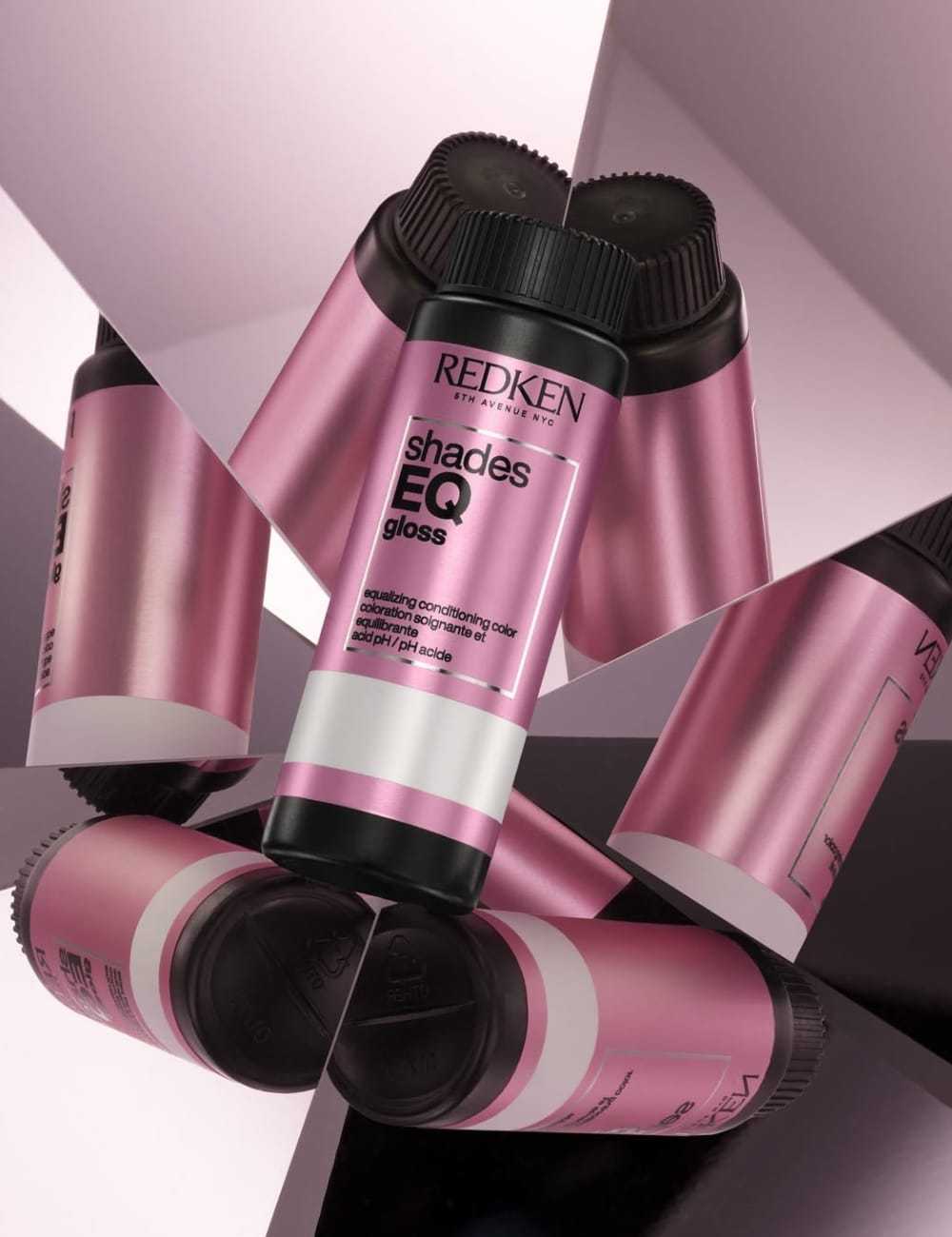Pink Redken Shades EQ Gloss bottles in a mirrored, geometric arrangement.