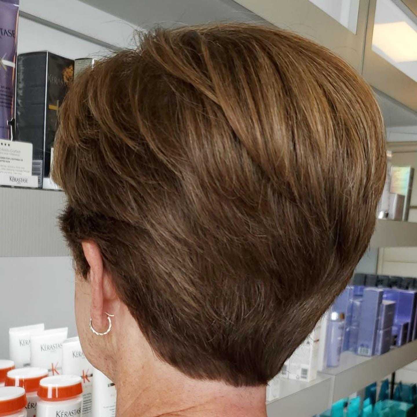 Close-up of a short brown hairstyle in a salon setting.