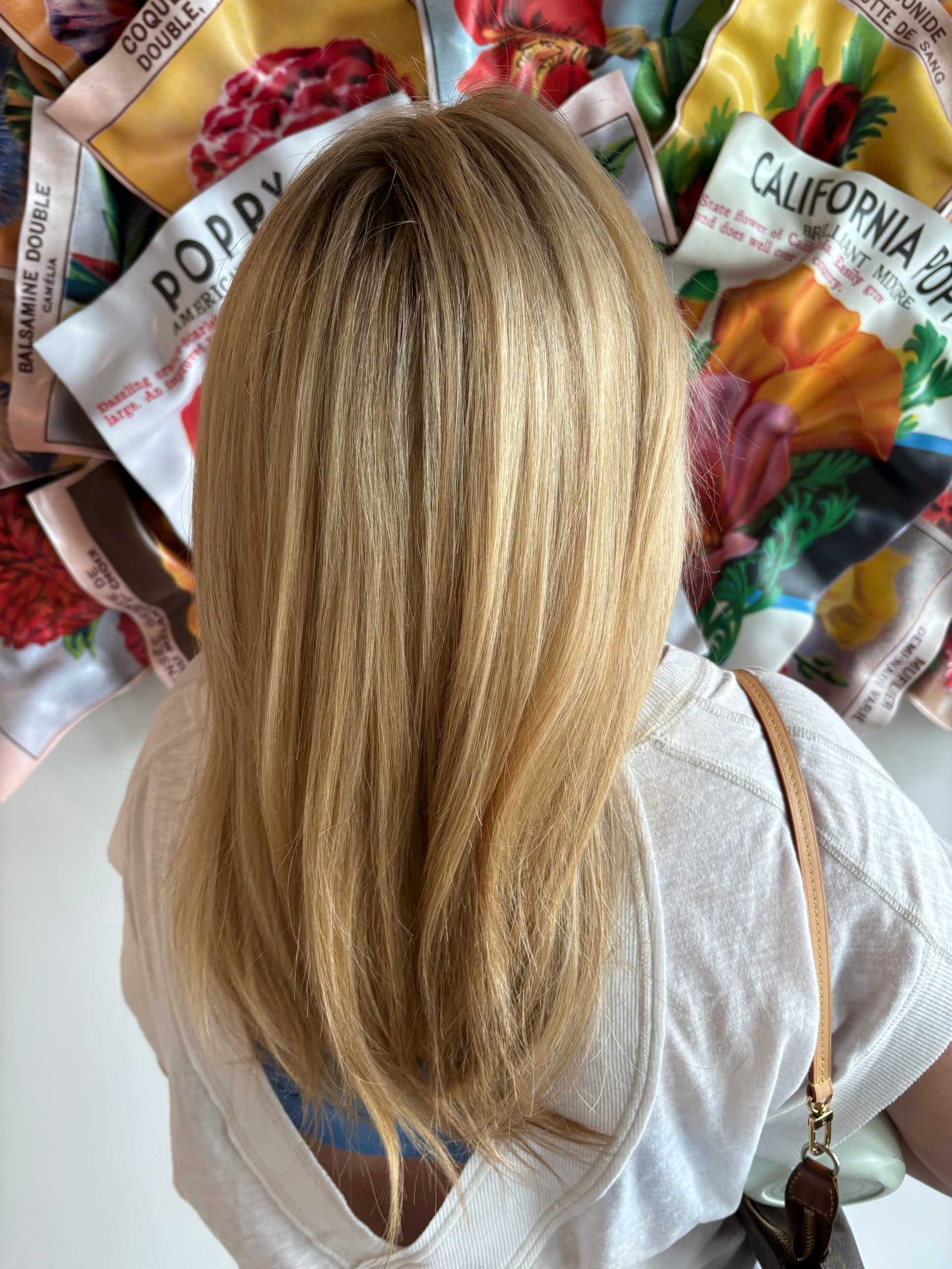 Blonde hair close-up with vibrant, colorful flower seed packets displayed in the background.
